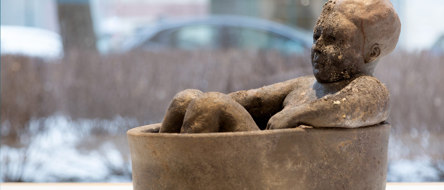 Vor dem Schaufenster der Galerie Handwerk ein Keramik-Objekt, das eine badende Frau in einer Wanne darstellt.