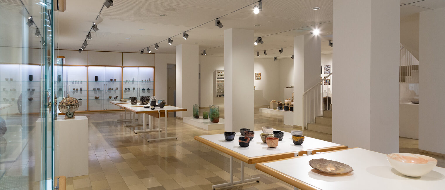 Impression der Ausstellung "Der Brand" im Untergeschoß der Galerie Handwerk. Keramikobjekte in Vitrinen und auf Tischen