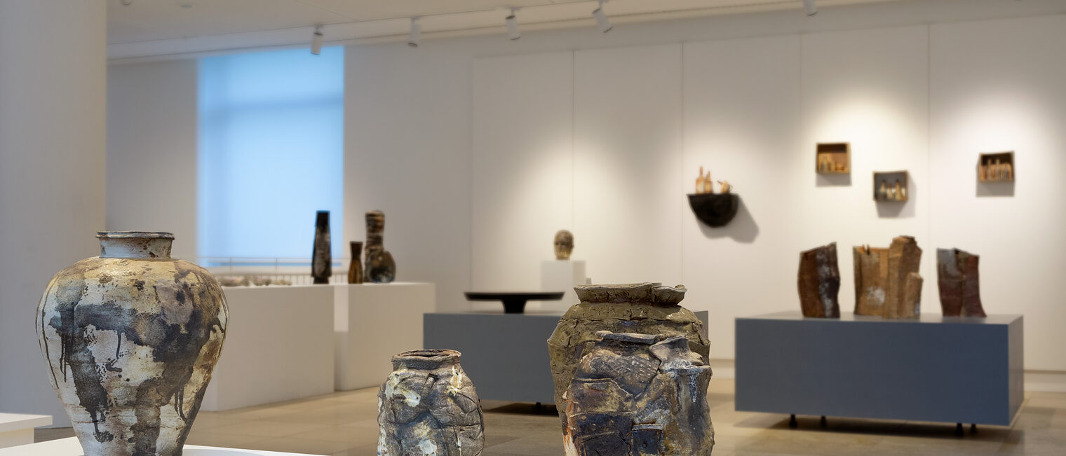 Im Vordergrund drei Keramik-Amphoren, die durch eine spezielle Brenntechnik stark marmoriert wirken. Dahinter diverse Objekte