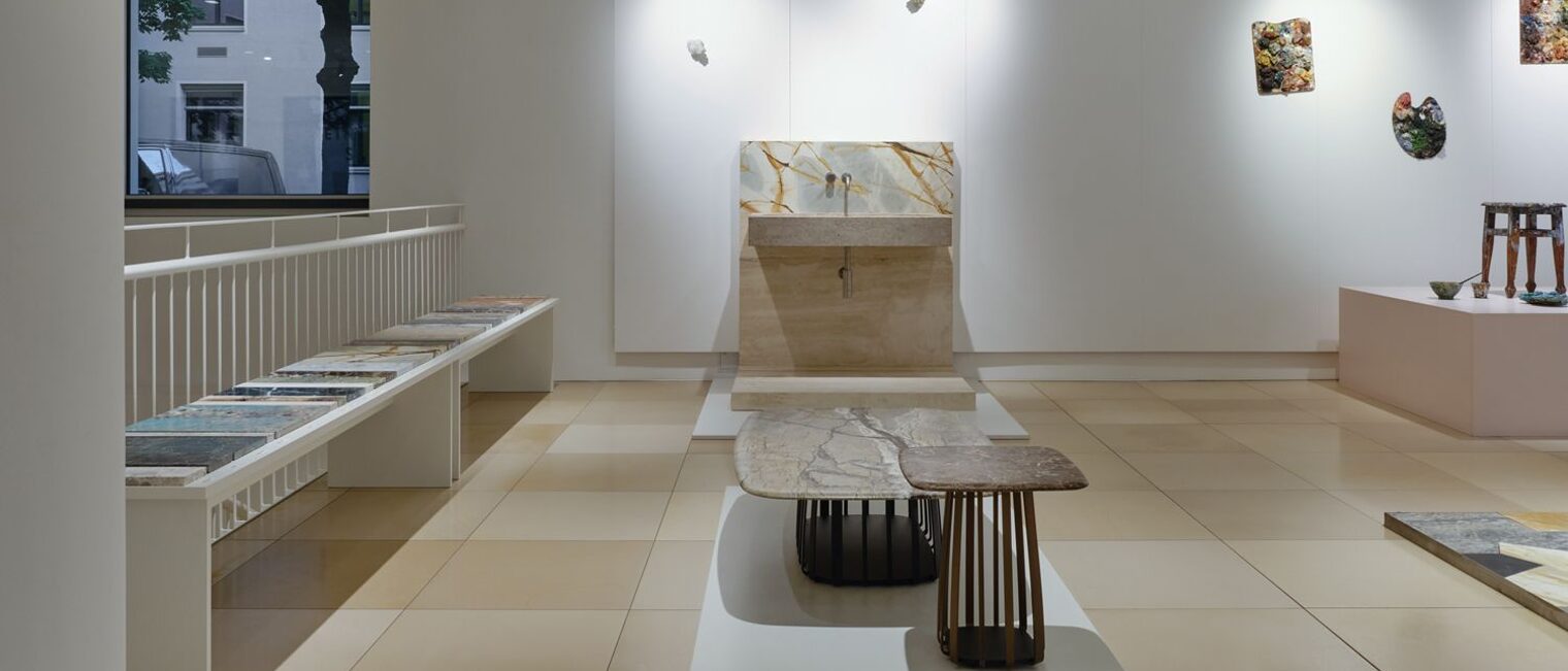  Im Vordergrund zwei Tische. Ein Coffee table aus braunem Stein auf einem runden Metallgitter fußend, ein anderer aus Marmor.